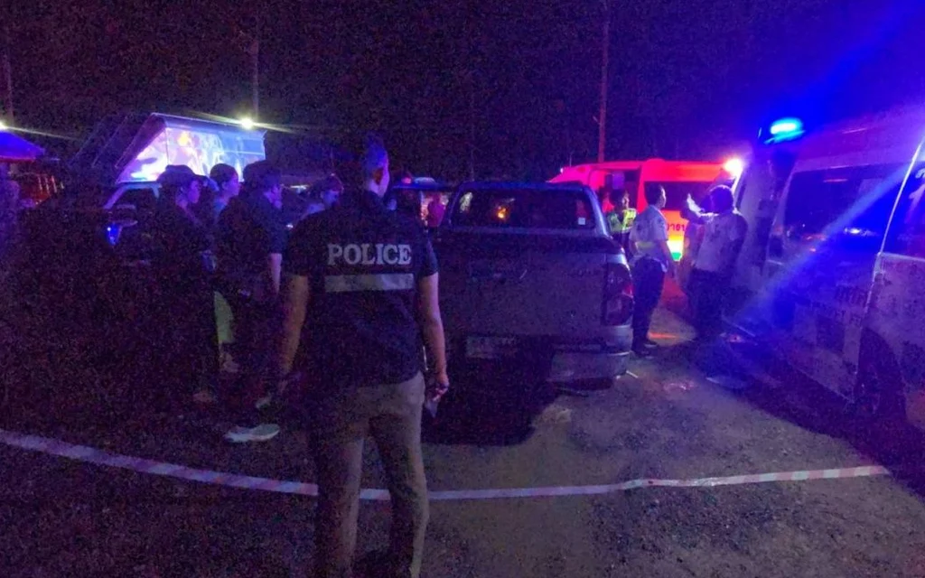 Police officers at a night crime scene with emergency vehicles.