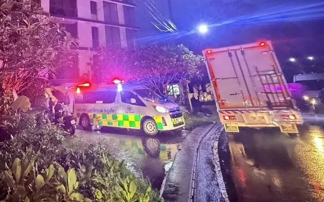 Emergency responders and a truck on a wet road at night.
