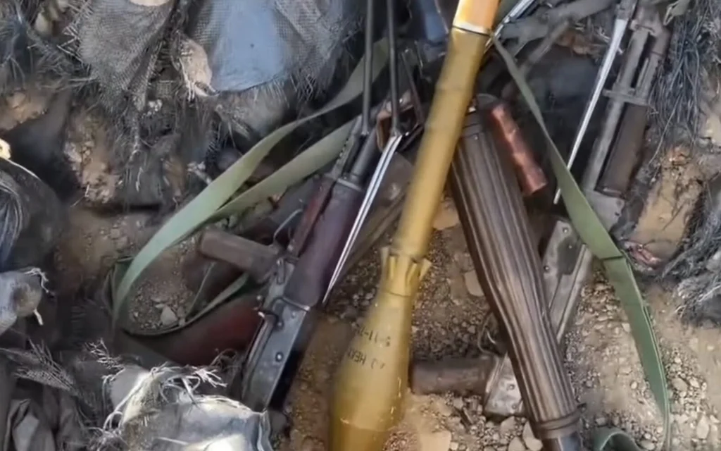 Several firearms and ammunition lie among debris and gear.
