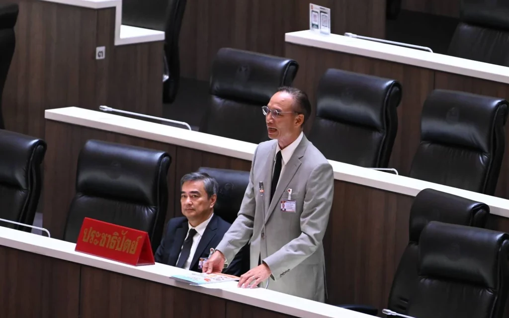Two men in suits at a desk in a parliamentary chamber.