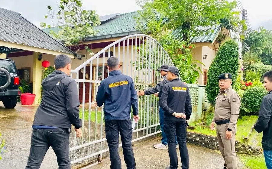 Immigration officers and police outside a gated house