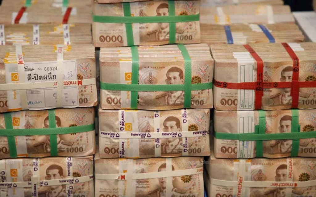 Stacks of bundled Thai banknotes secured with colored paper bands.