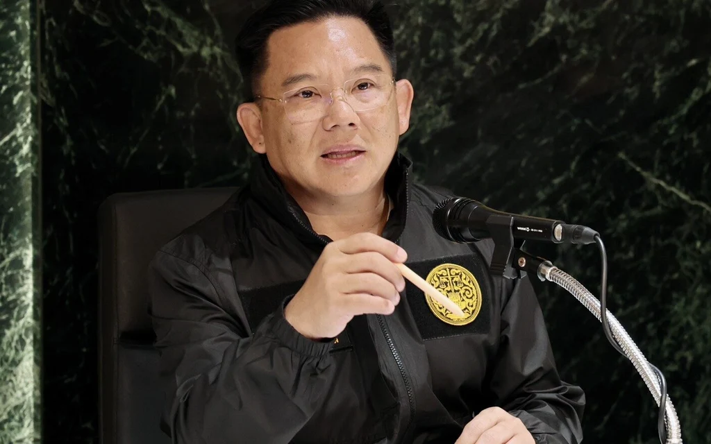 A man speaks at a microphone while holding a small object.