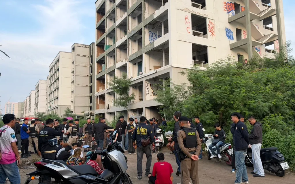 Police officers at a raid site with abandoned buildings.