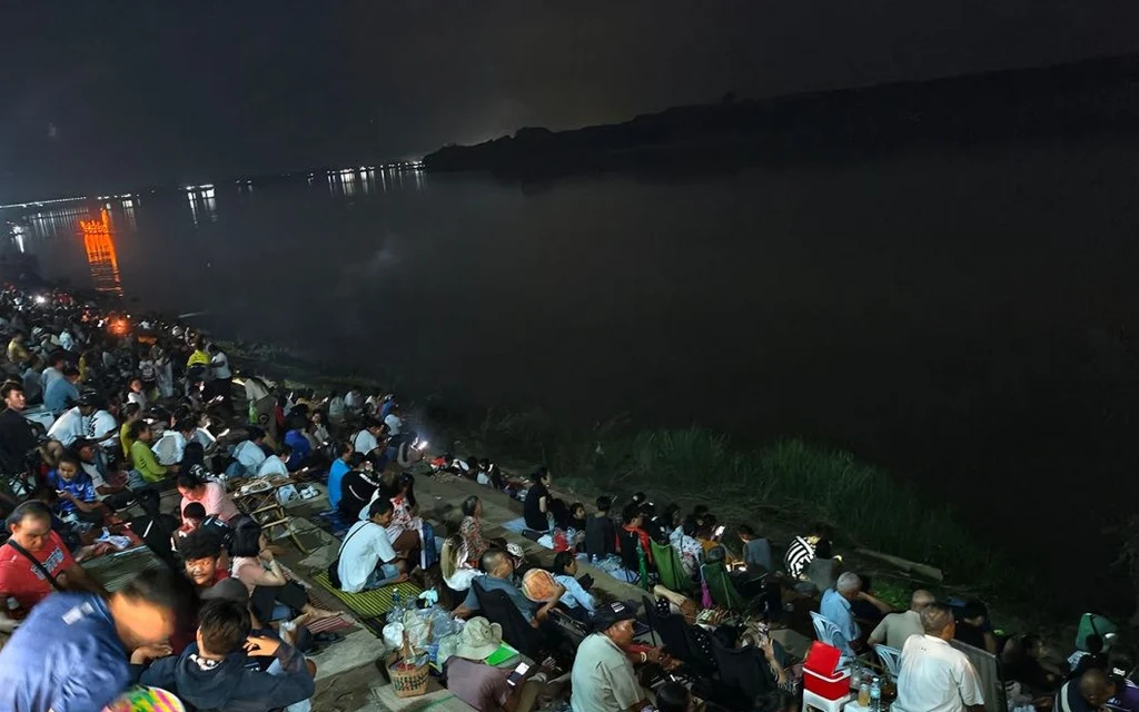 Crowds gather along the Mekong River at night to watch Naga fireballs.