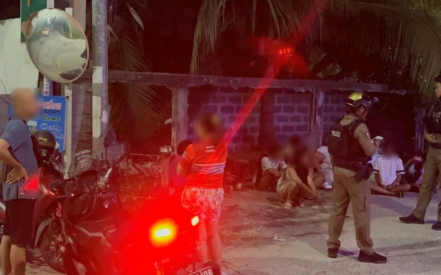 Police officers at a scene with teenagers sitting outside.