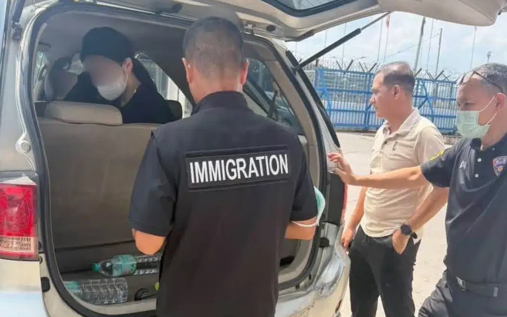 Immigration officers inspecting a vehicle with a suspect inside.