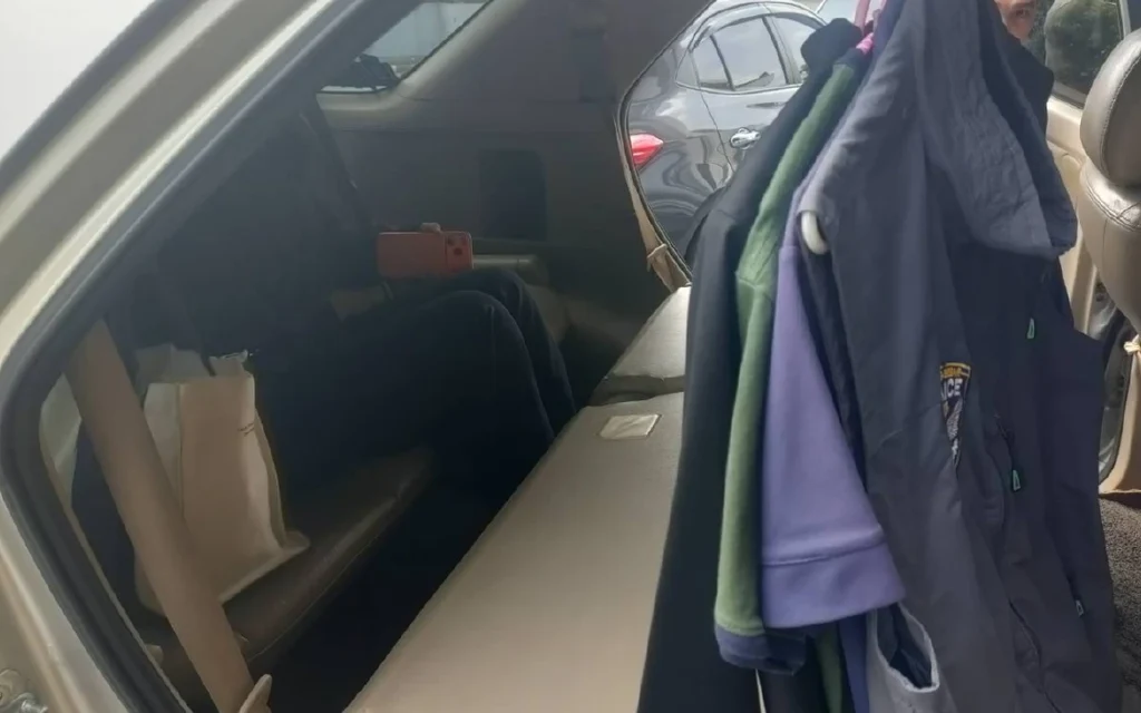 Interior of a vehicle with clothes hanging and a person sitting.