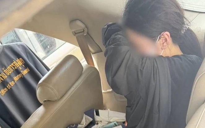 A person in custody sitting in a car.
