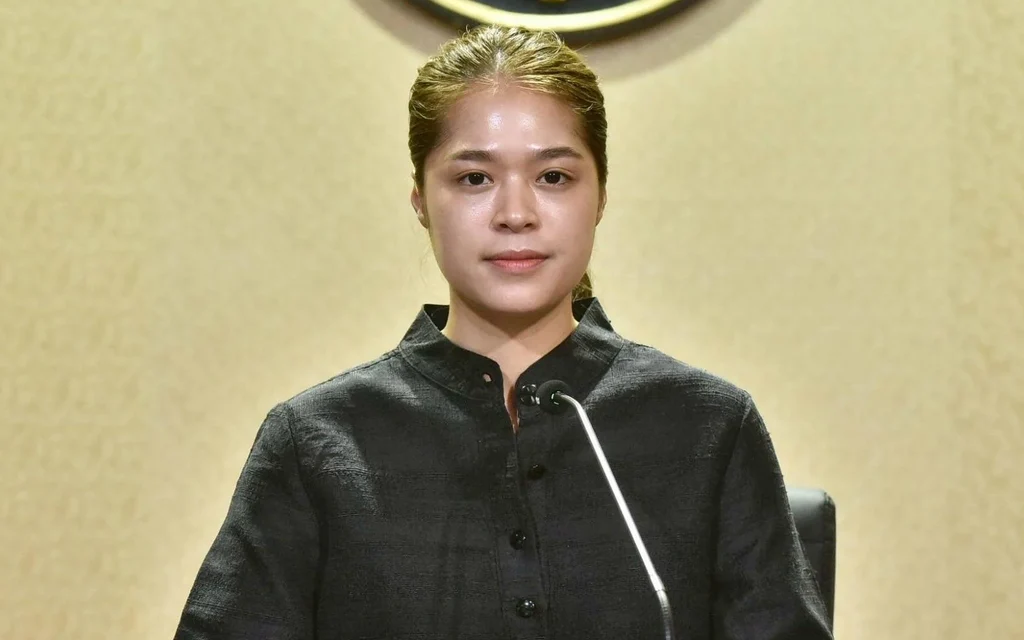 A woman in a black shirt speaking at a press conference.