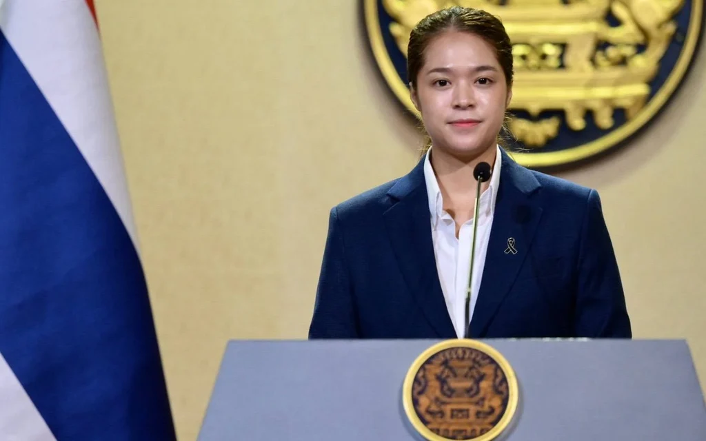 A woman speaking at a podium with the Thai flag behind.