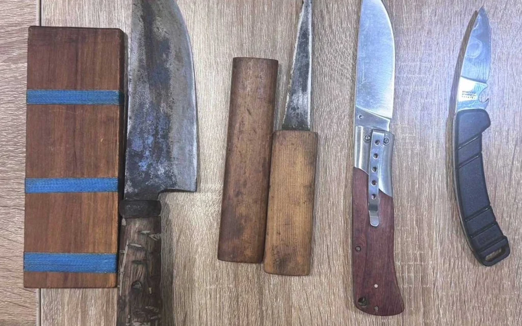Several knives and wooden handles laid out on a wooden surface.