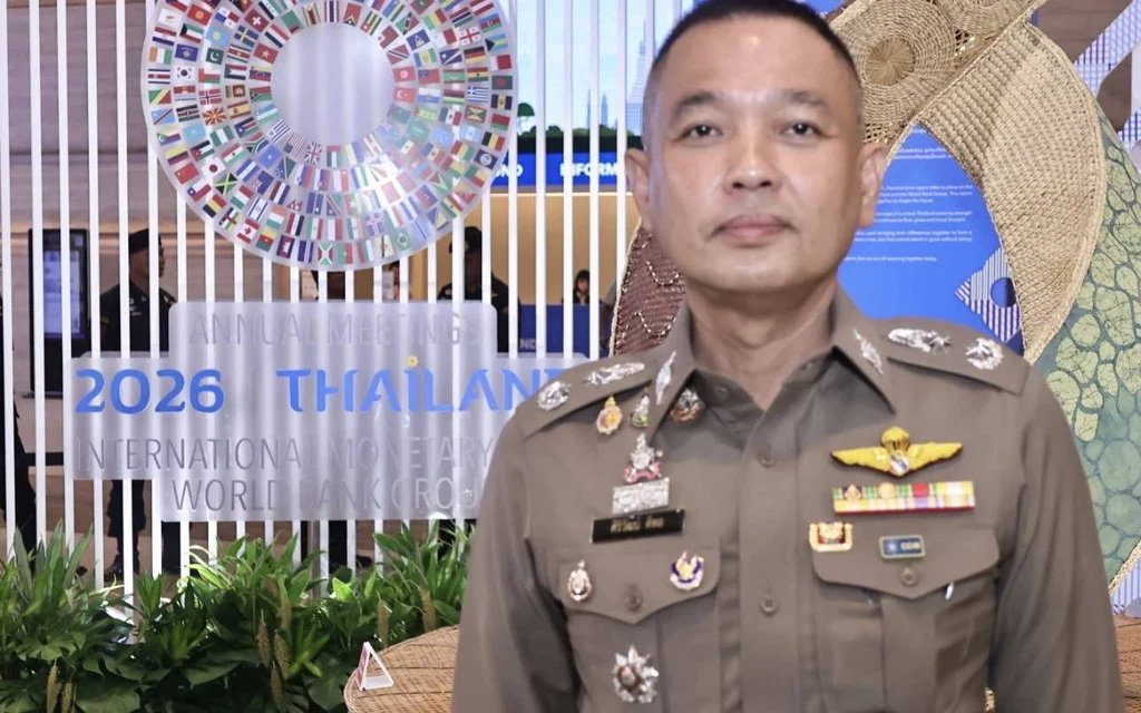 A Thai police officer standing in front of an event backdrop.