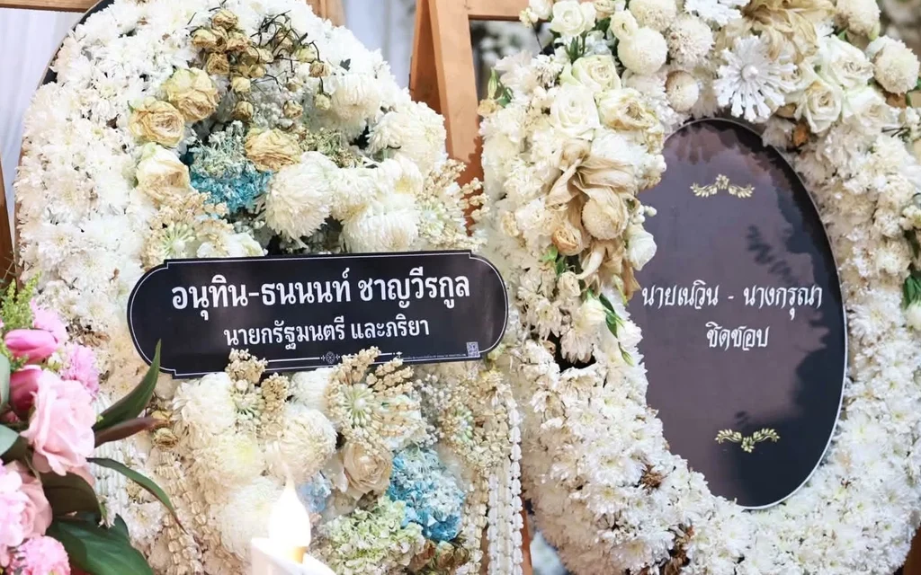 Floral funeral wreaths with Thai condolence messages at a memorial service