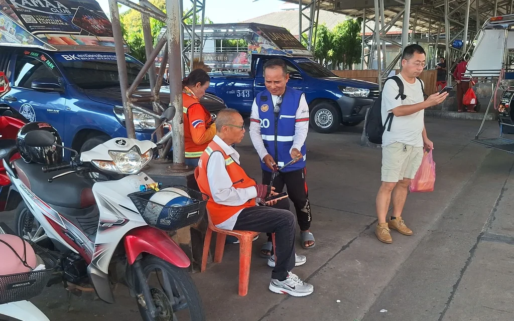 Motorcycle taxi drivers and blue-vested officials at a transport station.