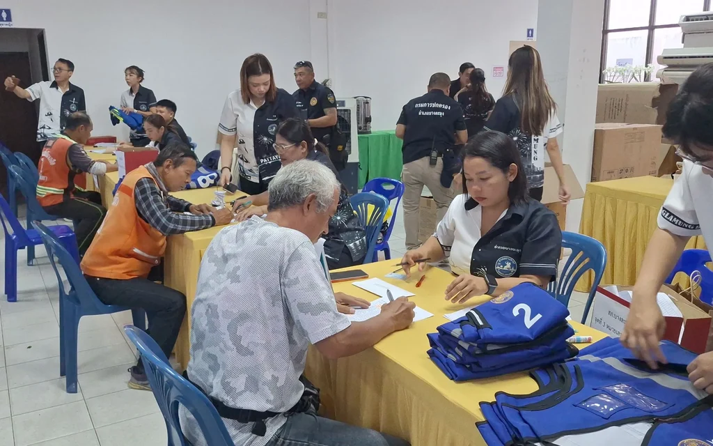 Officials distribute motorcycle taxi vests and assist people at registration tables.