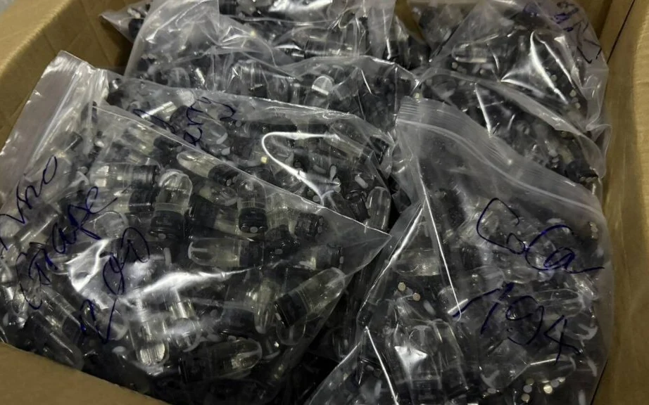 A cardboard box filled with small devices sealed in plastic bags.
