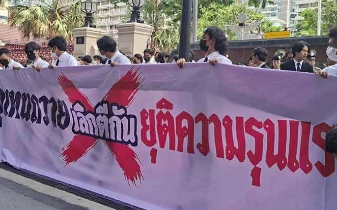 Students hold a Thai banner announcing an end to violence.