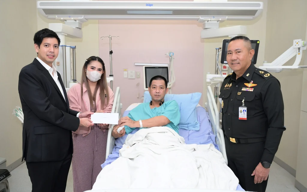 Representatives donating money to an injured soldier in a hospital bed.