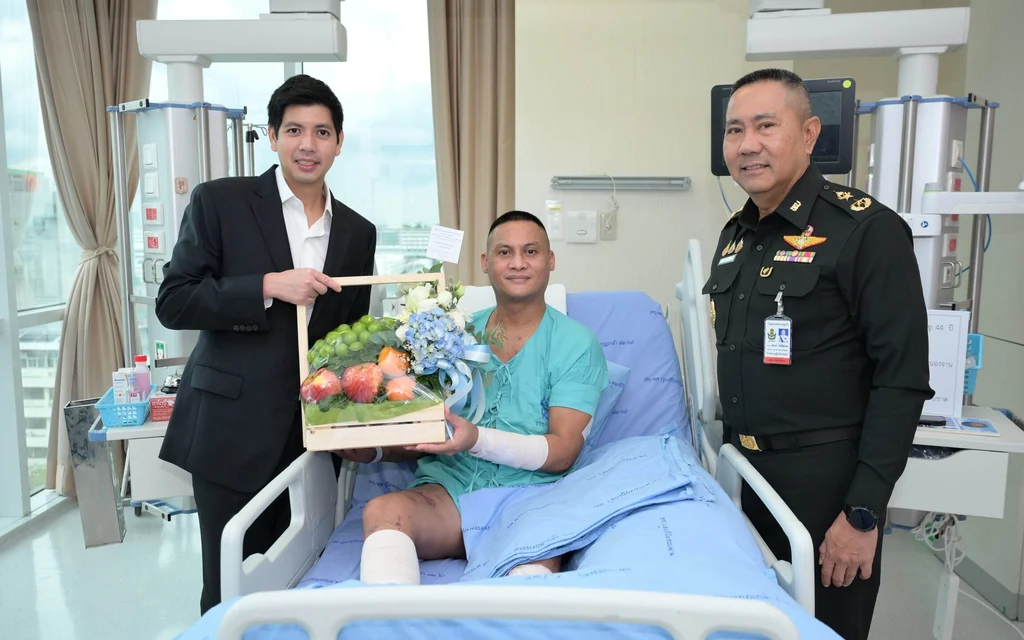 A man in a suit visits an injured soldier in hospital.