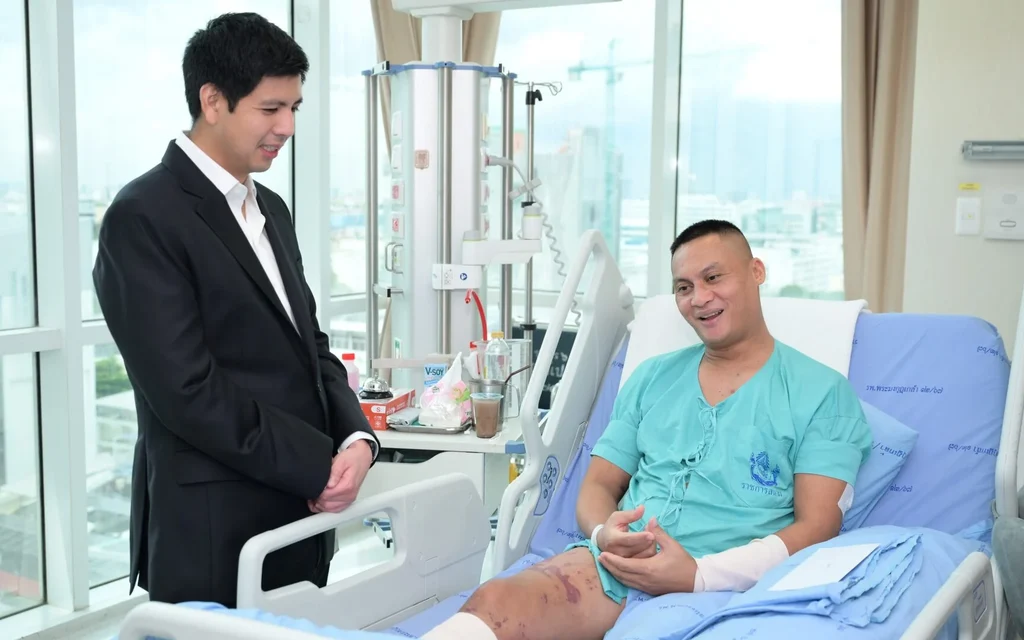 A man in a suit visiting an injured soldier in hospital.