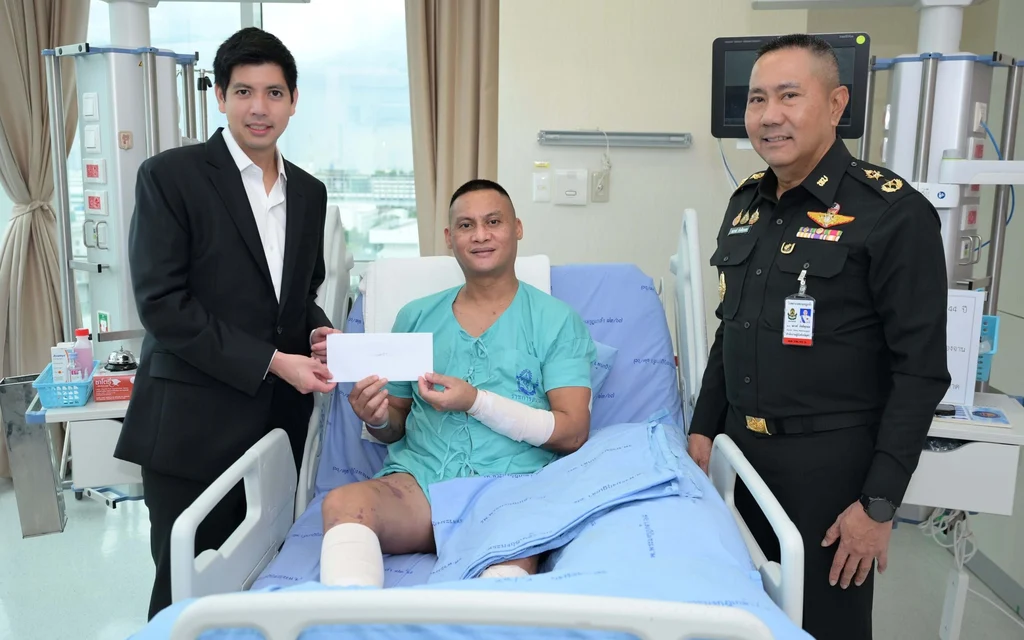 A man in a suit presents a donation to an injured soldier.