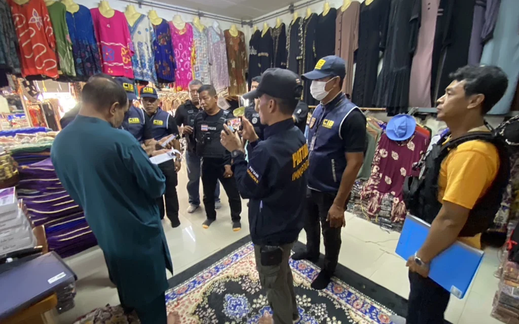 Police officers inspecting clothing inside a shop with colorful garments