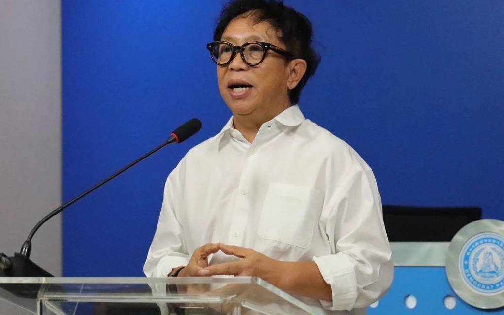 A man speaking at a podium with a blue background.
