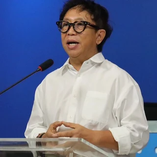 A man speaking at a podium with a blue background.