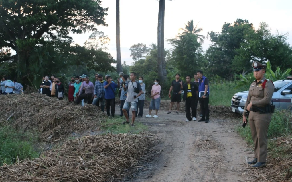 Police officer and onlookers at a rural canal-side scene